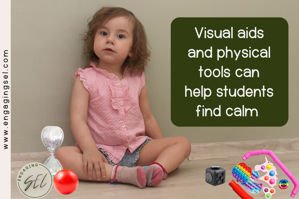 Student in the classroom sitting in a calm down area with a sand timer, stress ball, puzzle cube, pop-it and other fidgets. 